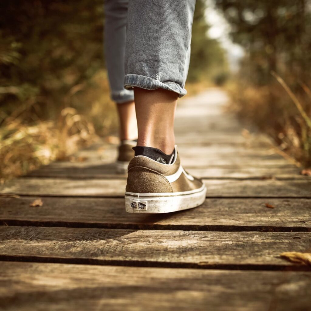 close up of someone walking a wooden boardwalk path in sneakers